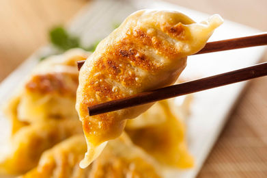 Crispy pan-fried dumpling held by chopsticks