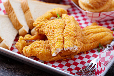 Golden fried fish fillets with bread on a checkered tray